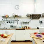 Kitchen of modern restaurant with variety of kitchenware and fresh vegetables on tables