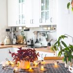 Purple oxalis in a pot with a face in the interior of the house in the kitchen, illuminated by garland lamps. Potted plant in a green house